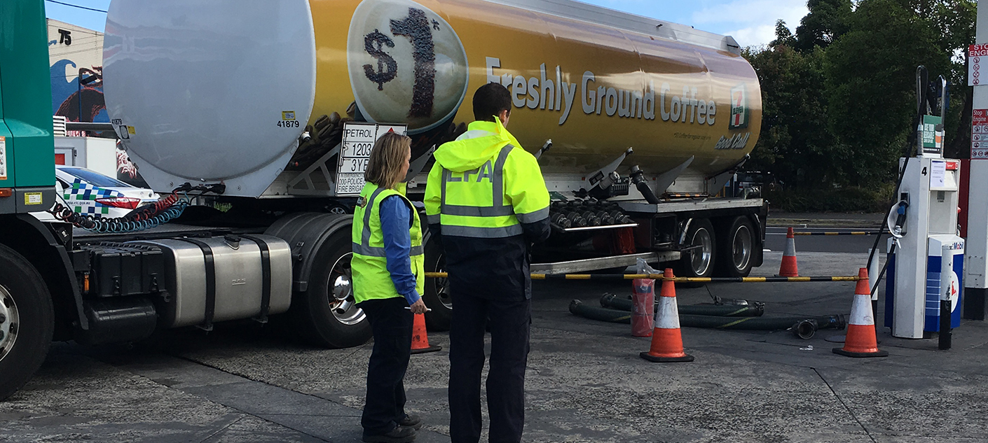 Two EPA staff overseeing a fuel truck in a fuel station that has been cordoned off